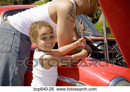 Stock Photograph - Young boy holding tools for his mechanic father . Fotosearch