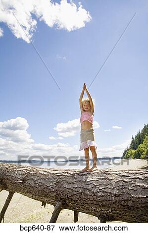 Stock Photo - Young girl balancing on fallen tree. Fotosearch