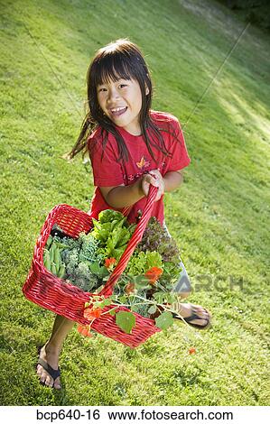Young girl carrying basket of plants outdoors View Large Photo Image Stock Photograph - Young girl carrying basket of plants outdoors. Fotosearch