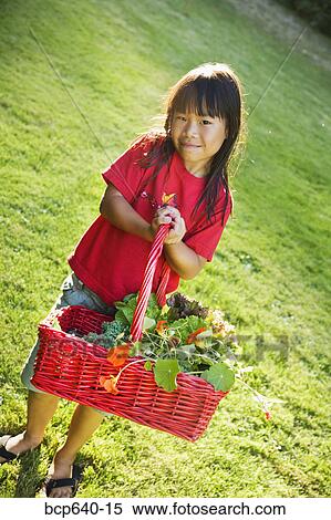 Young girl carrying basket of plants outdoors View Large Photo Image Stock Photography - Young girl carrying basket of plants outdoors. Fotosearch