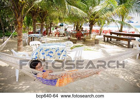 Picture - Young girl relaxing in hammock on beach. Fotosearch