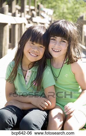 Young girls sitting together View Large Photo Image Stock Photograph - Young girls sitting together. Fotosearch