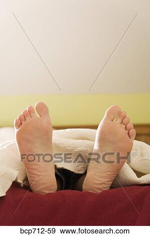 Bare feet sticking out from blanket View Large Photo Image Stock Photo - Bare feet sticking out from blanket. Fotosearch