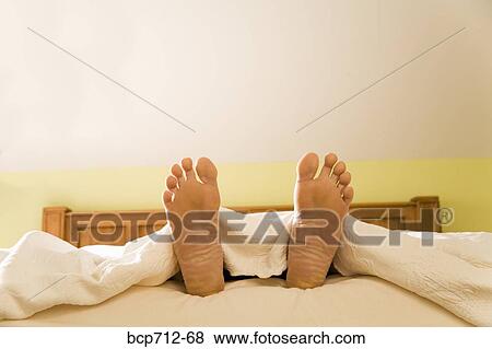 Stock Photo - Bare feet sticking out from blanket. Fotosearch