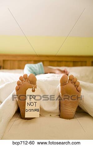 Stock Image - Bare feet with Do Not Disturb sign. Fotosearch