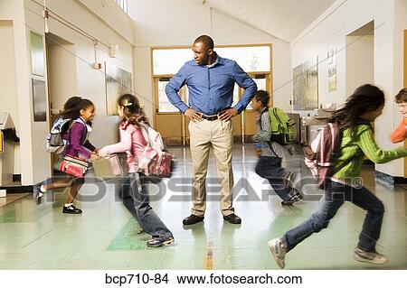 Picture - Blurred motion shot of students running past teacher. Fotosearch