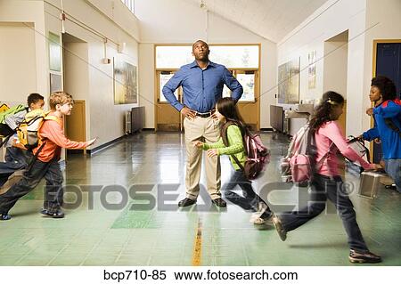 Stock Photography - Blurred motion shot of students running past teacher. Fotosearch