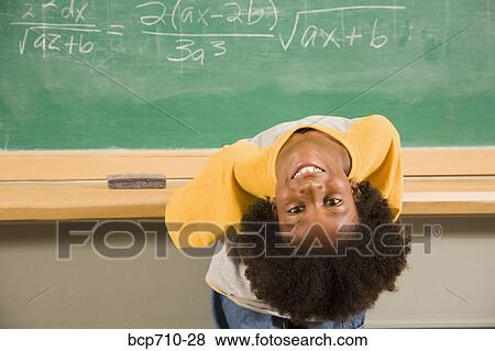 Stock Photo - Boy bending over backward in front of blackboard. Fotosearch
