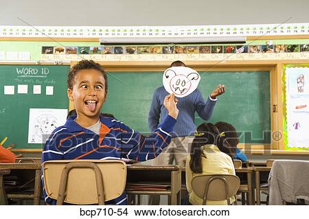 Boy holding drawing over teacher’s face View Large Photo Image Picture - Boy holding drawing over teacher’s face. Fotosearch