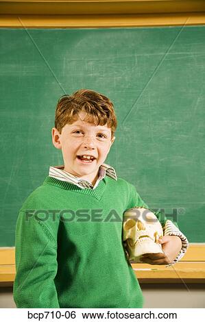 Boy holding skull in classroom View Large Photo Image Stock Photograph - Boy holding skull in classroom. Fotosearch