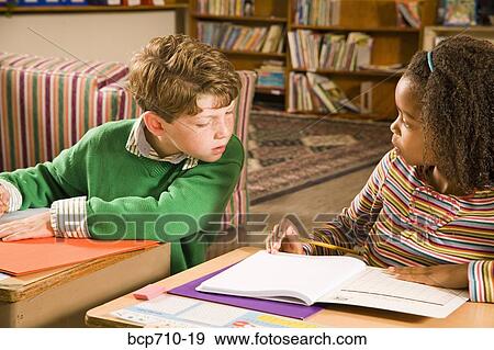 Boy looking at girl’s paper in classroom View Large Photo Image Stock Photo - Boy looking at girl’s paper in classroom. Fotosearch
