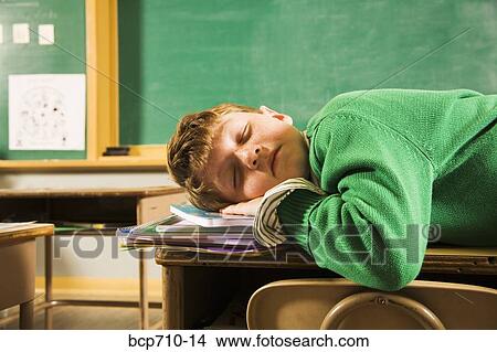 Boy sleeping on desks in classroom View Large Photo Image Picture - Boy sleeping on desks in classroom. Fotosearch