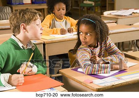 Boy trying to look at girl’s paper in classroom View Large Photo Image Stock Image - Boy trying to look at girl’s paper in classroom. Fotosearch