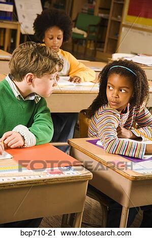 Boy trying to look at girl’s paper in classroom View Large Photo Image Stock Image - Boy trying to look at girl’s paper in classroom. Fotosearch