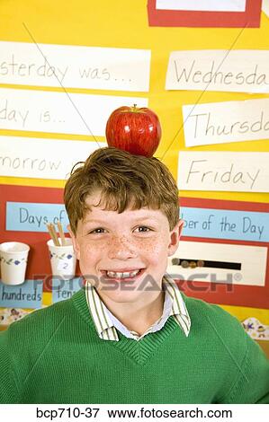 Stock Photo - Boy with apple on head in classroom. Fotosearch