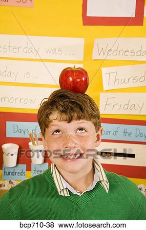 Stock Photo - Boy with apple on head in classroom. Fotosearch