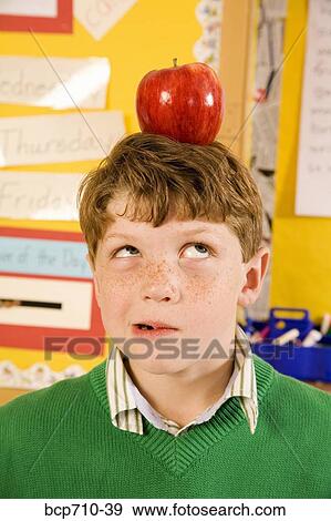 Boy with apple on head in classroom View Large Photo Image Stock Photo - Boy with apple on head in classroom. Fotosearch