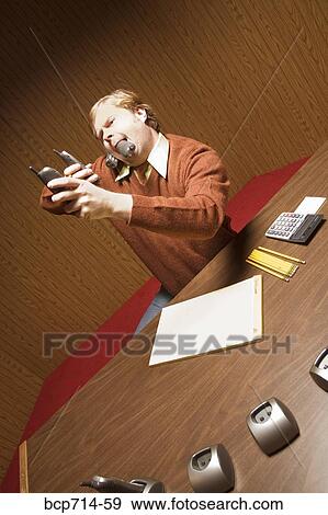 Businessman at desk using multiple telephones View Large Photo Image Stock Photo - Businessman at desk using multiple telephones. Fotosearch