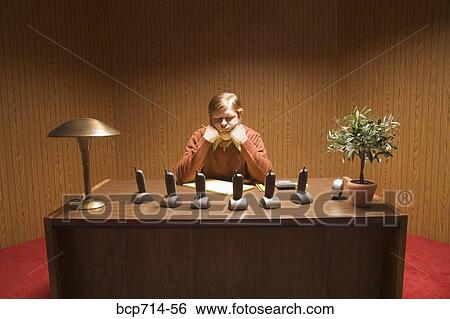 Stock Photograph - Businessman at desk with multiple telephones. Fotosearch
