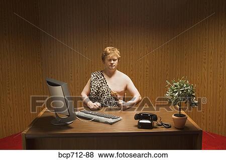 Businessman dressed as caveman at desk View Large Photo Image Stock Photo - Businessman dressed as caveman at desk. Fotosearch