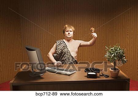 Stock Photo - Businessman dressed as caveman at desk. Fotosearch