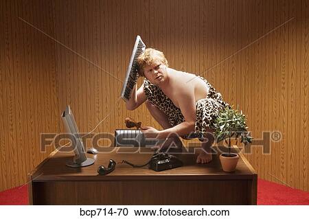 Businessman dressed as caveman crouching on desk View Large Photo Image Stock Image - Businessman dressed as caveman crouching on desk. Fotosearch