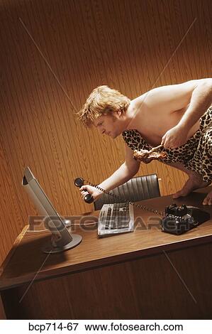 Businessman dressed as caveman crouching on desk View Large Photo Image Stock Photo - Businessman dressed as caveman crouching on desk. Fotosearch
