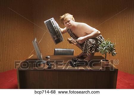 Businessman dressed as caveman crouching on desk View Large Photo Image Stock Photo - Businessman dressed as caveman crouching on desk. Fotosearch