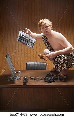 Businessman dressed as caveman crouching on desk View Large Photo Image Stock Photo - Businessman dressed as caveman crouching on desk. Fotosearch