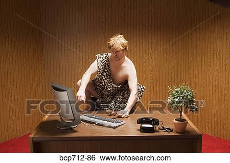 Businessman dressed as caveman crouching at desk View Large Photo Image Stock Photograph - Businessman dressed as caveman crouching at desk. Fotosearch