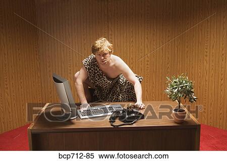 Businessman dressed as caveman crouching at desk View Large Photo Image Stock Photography - Businessman dressed as caveman crouching at desk. Fotosearch
