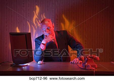 Businessman dressed as devil at desk View Large Photo Image Stock Photograph - Businessman dressed as devil at desk. Fotosearch