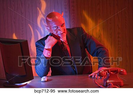 Businessman dressed as devil at desk View Large Photo Image Stock Photography - Businessman dressed as devil at desk. Fotosearch