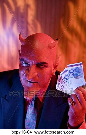 Businessman dressed as devil holding money View Large Photo Image Picture - Businessman dressed as devil holding money. Fotosearch