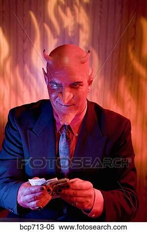 Businessman dressed as devil holding money View Large Photo Image Stock Photography - Businessman dressed as devil holding money. Fotosearch