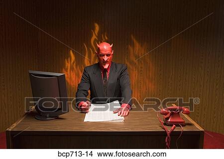 Picture - Businessman dressed as devil reading newspaper. Fotosearch