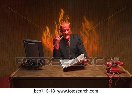 Stock Image - Businessman dressed as devil reading newspaper. Fotosearch
