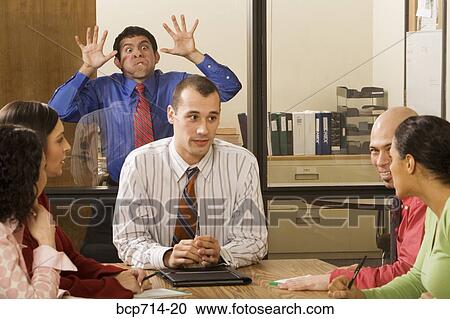 Businessman making faces through glass wall at co-workers View Large Photo Image Stock Image - Businessman making faces through glass wall at co-workers. Fotosearch