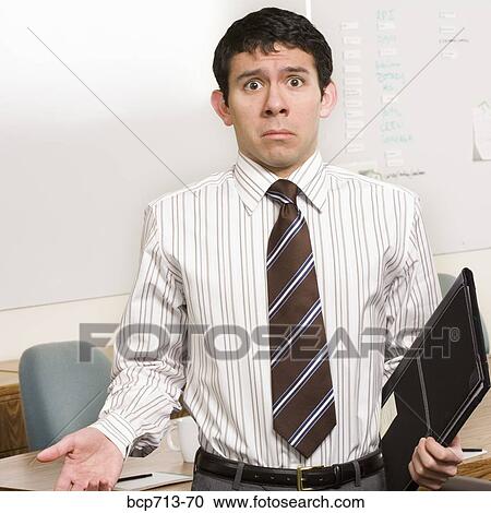 Businessman shrugging shoulders in office View Large Photo Image Stock Image - Businessman shrugging shoulders in office. Fotosearch