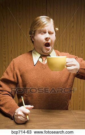 Businessman yawning and drinking coffee View Large Photo Image Stock Image - Businessman yawning and drinking coffee. Fotosearch