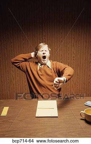 Picture - Businessman yawning and looking at watch. Fotosearch