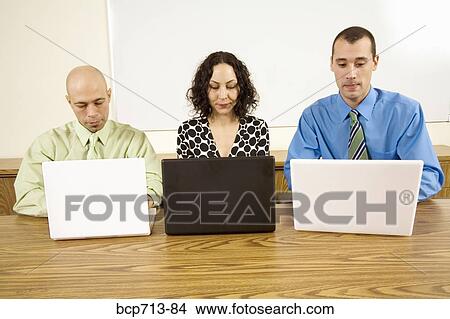 Businesspeople looking at laptops View Large Photo Image Picture - Businesspeople looking at laptops. Fotosearch