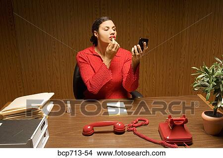 Businesswoman applying lipstick with telephone off the hook View Large Photo Image Picture - Businesswoman applying lipstick with telephone off the hook. Fotosearch