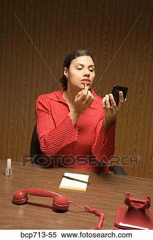 Businesswoman applying lipstick with telephone off the hook View Large Photo Image Stock Photography - Businesswoman applying lipstick with telephone off the hook. Fotosearch