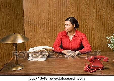 Stock Photo - Businesswoman at desk next to stack of files. Fotosearch