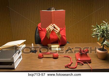 Businesswoman reading book with telephone off the hook View Large Photo Image Stock Photo - Businesswoman reading book with telephone off the hook. Fotosearch