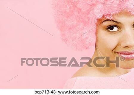 Stock Image - Close up of woman wearing pink wig. Fotosearch