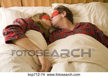 Couple kissing in bed with eye mask View Large Photo Image Picture - Couple kissing in bed with eye mask. Fotosearch