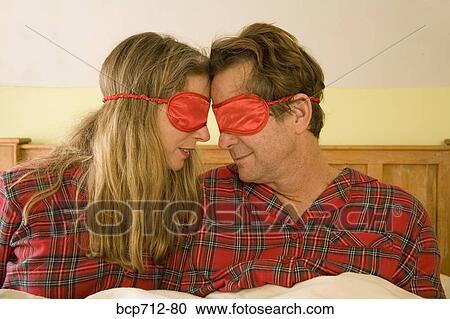 Couple sitting in bed wearing eye masks View Large Photo Image Stock Image - Couple sitting in bed wearing eye masks. Fotosearch