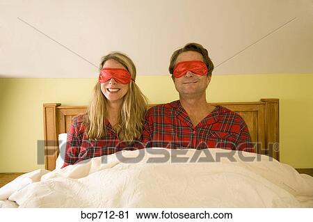 Couple sitting in bed wearing eye masks View Large Photo Image Stock Image - Couple sitting in bed wearing eye masks. Fotosearch